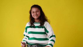 4k video of one girl showing thumbs up and smiling over yellow background.