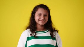 4k video of one young girl who smiles and winks her eye over yellow background.