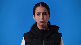4k video of one girl who is disappointed and bows her head over blue background.