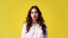 4k video of one girl thinking about something and showing pointing up on yellow background.