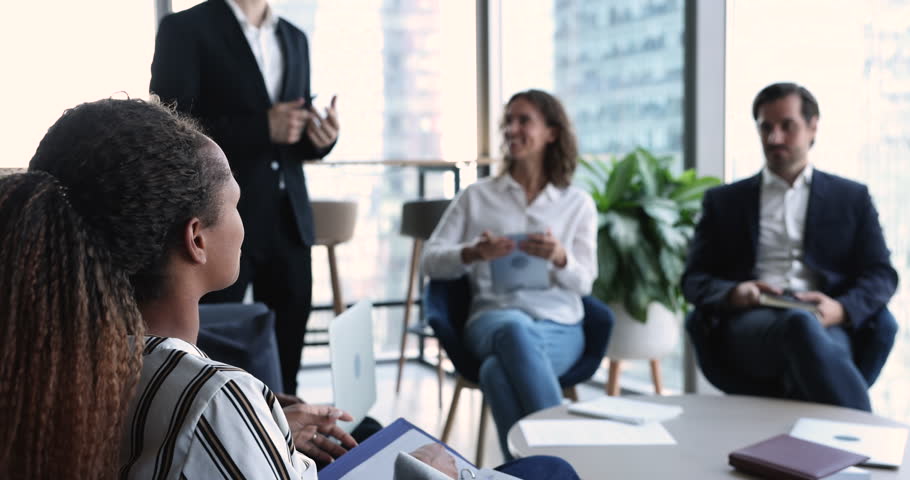 Employees attend group meeting listen to African businesswoman, make speech, share information, ideas, planning project with colleagues gathered in office for search solution, thinking, brainstorming Royalty-Free Stock Footage #1100909975
