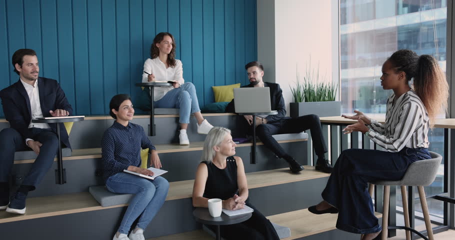 Multiracial team listen African woman, business trainer during training in co-working space. Corporate seminar, new knowledge, develop skills, university educational workshop event in modern auditory Royalty-Free Stock Footage #1100909989