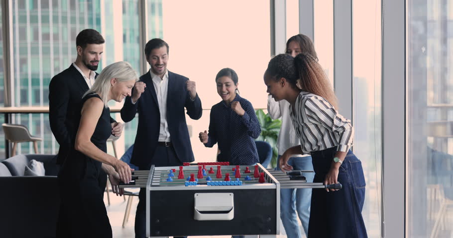 Happy six multi ethnic employees gathered together at lunch break, excited group of people supporting, cheering women colleagues playing foosball game, scream with joy, relish victory giving high five Royalty-Free Stock Footage #1100910073