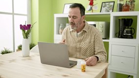 Middle age man using laptop having online medical consultation at home