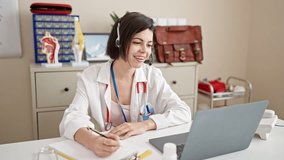 Young caucasian woman doctor on a video call writing on clipboard at clinic