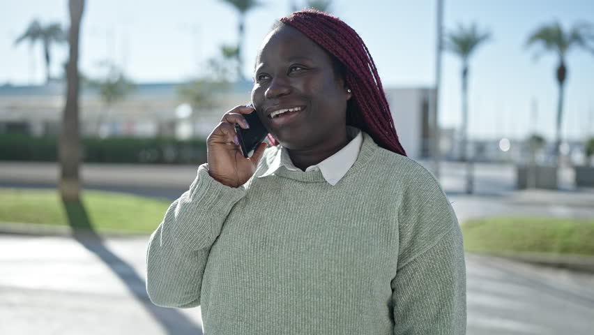African woman with braided hair speaking on the phone at street