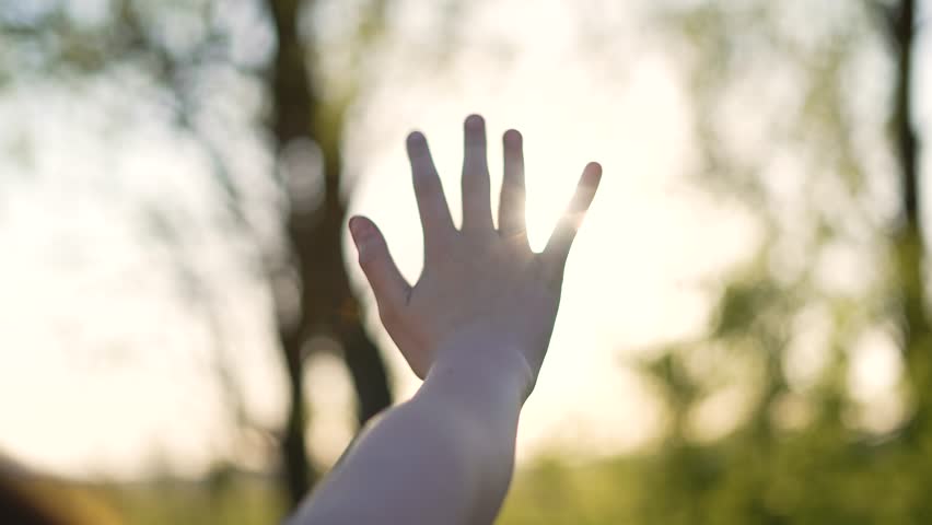 Happy girl stretches her hands to sun. Children palm in rays of sun at sunset.Young woman raising her hands praying at sunset or sunrise.Freedom in nature and spirituality concept.Fingertips touch sun Royalty-Free Stock Footage #1100918011