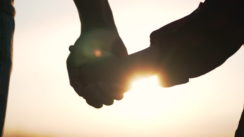 Silhouette of parent, small child holding hands at sunset. Happy family holding hands together. parent takes care of child. Hands at sunset silhouette. Take child by hand. | Shutterstock HD Video #1100918045