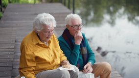 Happy senior couple in autumn clothes having break near lake after walk. - Powered by Shutterstock - Get 15% off with code: PIKWIZARD15