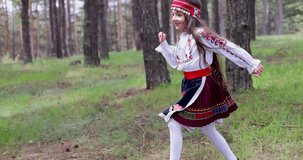 Bulgarian girl in traditional folklore costume running in forest of majestic mountain, 4k slow motion video. Bulgaria nature and people.