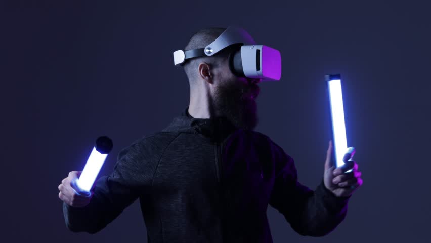 Man in futuristic costume. Guy in glasses of virtual reality while touching air. Augmented reality game, future technology, AI concept. VR. Neon blue light. Dark background.