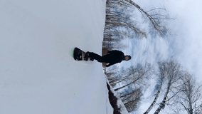 A man in black clothes snowboarding, a snowboarder with a 360 camera, shooting with a 360 camera, snowboarding, vertical shooting