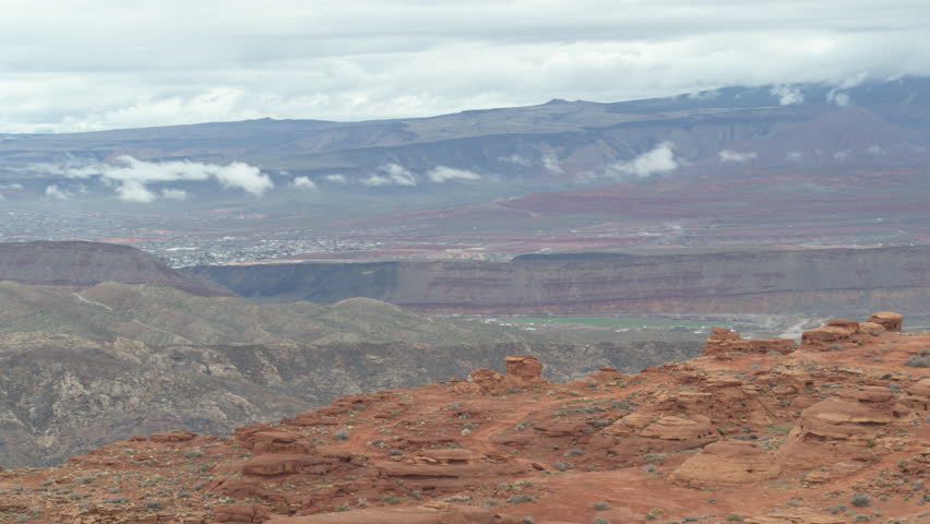 Aerial above Sand Hallow OHV Area near St. George Utah with red sand, desert buttes and snow capped mountain peaks