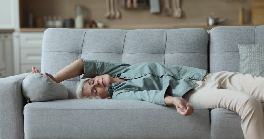 Overloaded powerless mature woman come back home and flopped down on sofa in living room feels without energy and too exhausted, squeezed like lemon after long hard working day. Rest, lack of strength | Shutterstock HD Video #1100936545