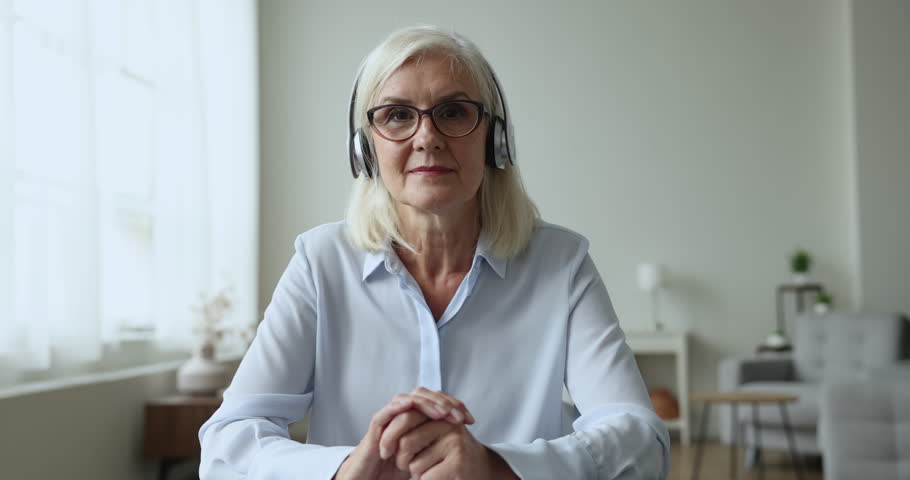 Mature female, certified psychologist gives support, provide professional help to client remotely wear headphones looks at camera talk, use video call app. Workflow of psychological on-line counsellor Royalty-Free Stock Footage #1100936555