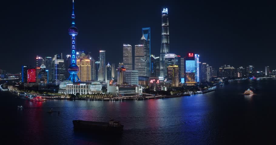 Aerial night view of the Bund in Shanghai, passing through historic buildings to see Lujiazui.