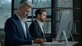 Focused professional managers working with computers on project sit in row at desk in office caucasian adult business men businessmen corporate employees colleagues work on Internet typing on computer - Powered by Shutterstock - Get 15% off with code: PIKWIZARD15