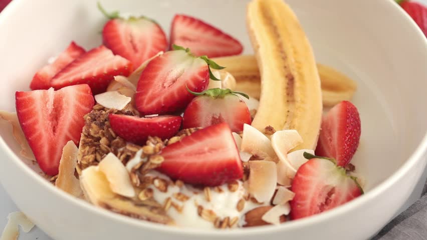 Healthy vegan banana split with Greek yogurt, strawberries, homemade granola and organic peanut butter. Royalty-Free Stock Footage #1100944151