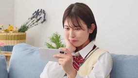 Asian high school student watching the smartphone at home