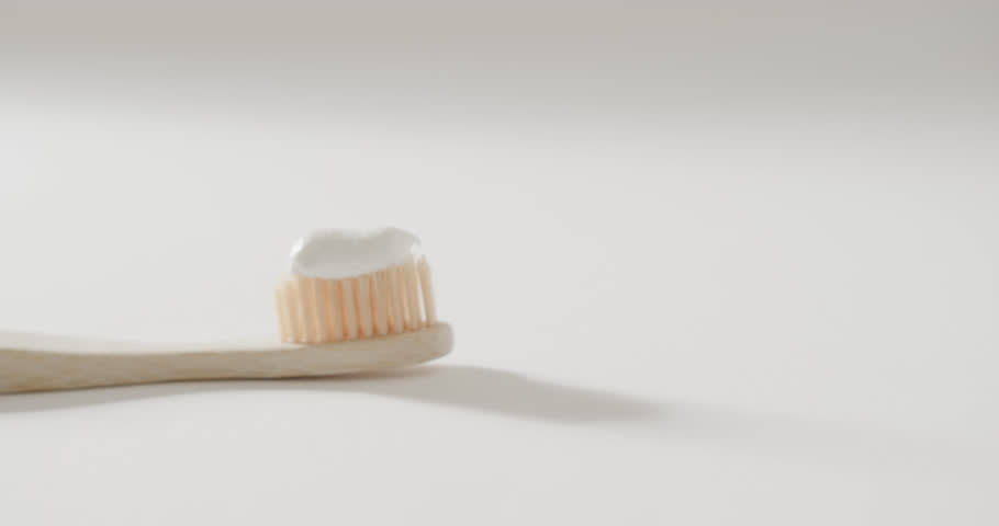 Close up of toothbrush with toothpaste on white background with copy space. Plastic free beauty and eco packaging concept.