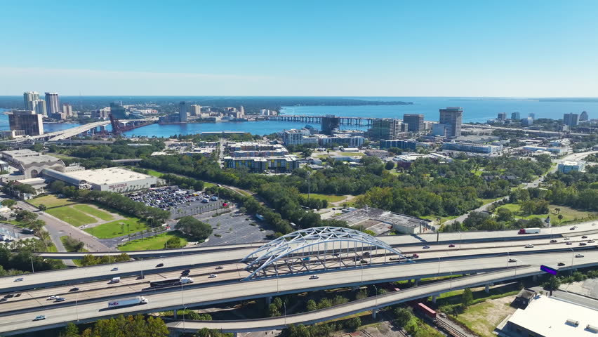 Aerial view of Jacksonville city with high office buildings and american freeway intersection with fast driving cars and trucks. View from above of USA transportation infrastructure