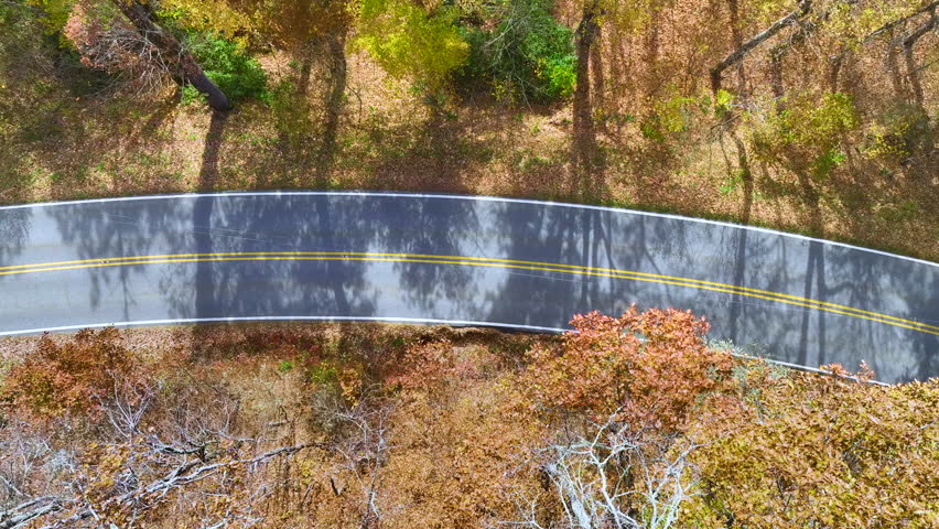Aerial view of empty scenic Blue Ridge Parkway road in Appalachian mountains winding between yellow woods in fall season. Traveling in North Carolina