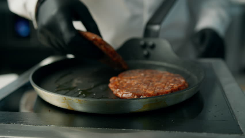 professional kitchen: the chef is frying patties for a burger