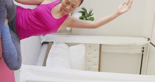 Vertical video of happy asian woman doing yoga and stretching in bedroom, in slow motion. Spending quality time, lifestyle and domestic life concept.