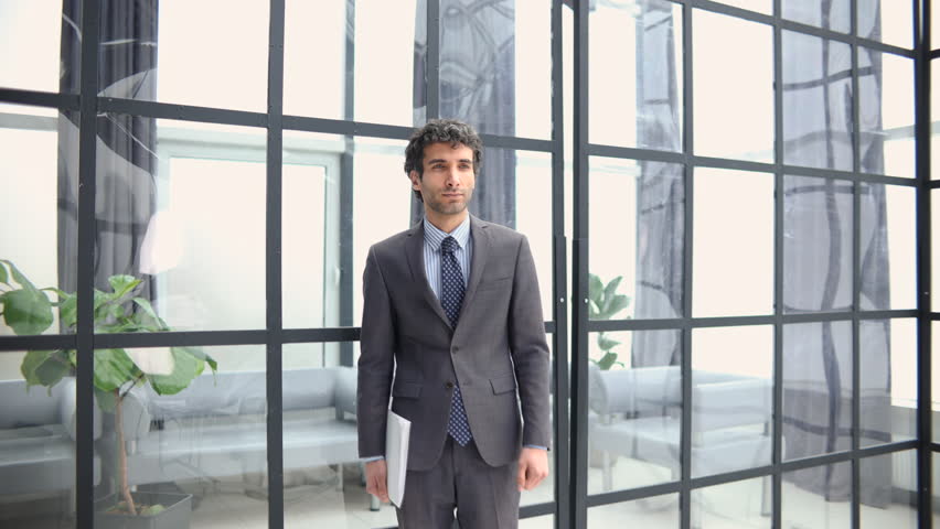 Young handsome businessman smiling and walking in an office environment