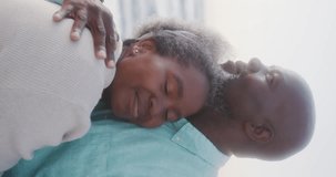 Vertical video of senior african american couple embracing at beach, in slow motion. Spending quality time, lifestyle, retirement and holiday concept.