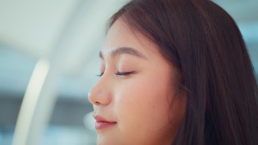 Close up - Attractive young asian woman opens his black eyes on a blurred background, Enjoy moment of peace, do mental relaxation exercises, feels no stress concept Royalty-Free Stock Footage #1100976709