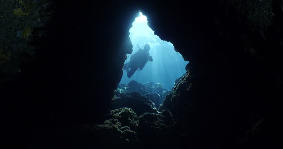 scuba divers underwater exploring the caves caverns and tunnels with sun beams and rays Royalty-Free Stock Footage #1100978323