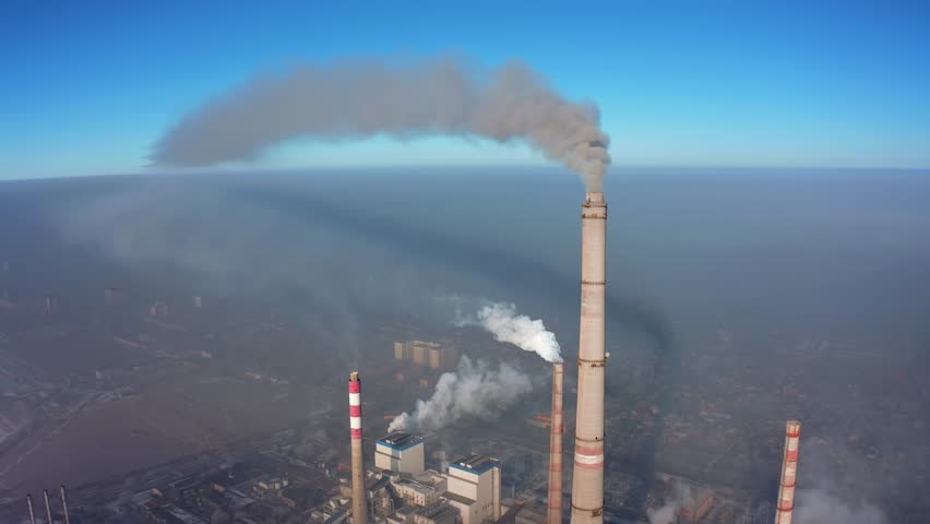 Pipes with toxic emissions pollute the atmosphere against the backdrop of a city in smog and gray smoke