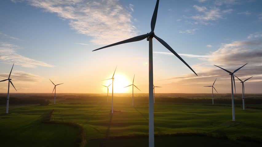Aerial footage  of  large spinning wind turbine in agriculture fields Aerial footage of rotating blades of wind turbine against sun. Aerial flying over renewable energy wind farm.  | Shutterstock HD Video #1100984039