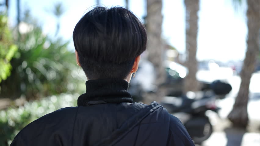 Young chinese woman standing on back view at park