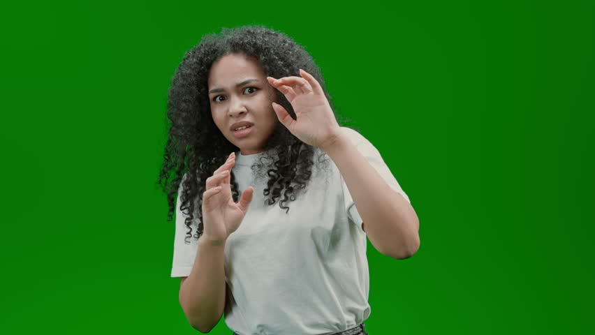 Frightened woman with curly long hair dressed white shirt express feel fear or anxiety Isolated on Green Screen | Shutterstock HD Video #1100985457
