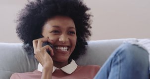 Those hour long phone calls with your bestie. 4k footage of an attractive young woman using a mobile phone while relaxing on the sofa at home.