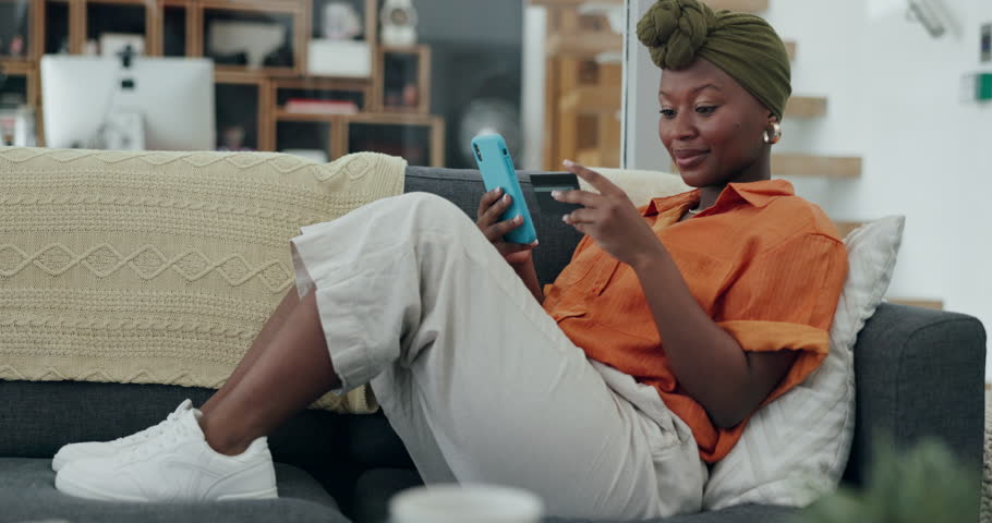 Credit card, smartphone and black woman online shopping payment on her home sofa excited for online shop sale, promotion or discount. Woman using phone for banking, e commerce and fintech mobile app Royalty-Free Stock Footage #1100991987