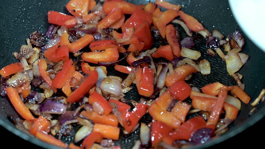 Sliced chicken added to sizzling peppers and onions in hot skillet
