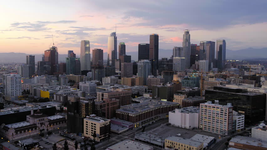 Aerial Shot Of Skyscrapers Under Cloudy Sky, Drone Flying Backward In City During Sunset - Los Angeles, California