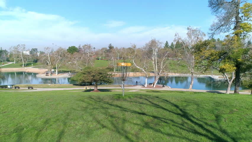 Aerial: Drone Backward Shot Of Green Landscape With Trees In Park Under Sky On Sunny Day - Los Angeles, California