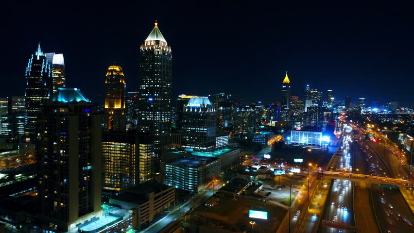 Aerial Panning Shot Of Illuminated Tall Building By Cars Moving On Roads In City At Night - Atlanta, Georgia