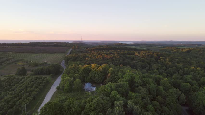 Aerial view of a summer cottage tucked away in the woods near the scenic M22 and Sleeping Bear Dunes and Traverse City Michigan at sunset with the light kissing the tops of the trees