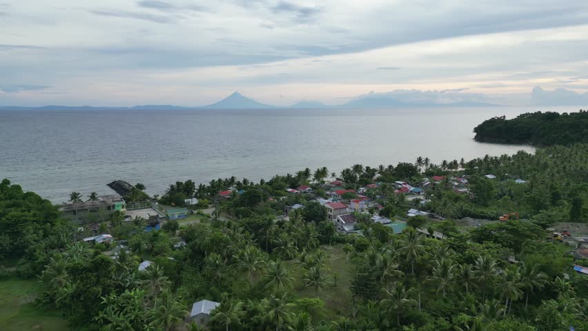 Aerial View of Rural Beachfront Town with silhouette of Mayon Volcano looming in background. Virac, Catanduanes, Philippines