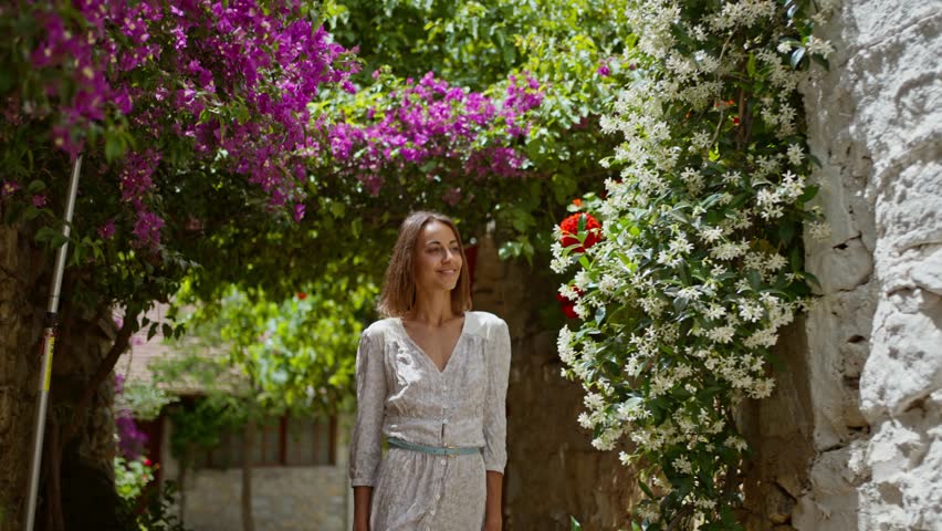 slow motion Smiling beautiful carefree woman wearing white dress walking street with flowers in old part of city enjoying vacation in Datcha, Turkey. Royalty-Free Stock Footage #1101002891