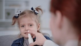 treatment of child for cold, portrait of cute girl dripping nose spray from runny nose due to virus or infection, close-up