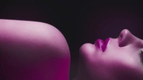 Vertical video. 90s fashion. Neon model. Retro 2000s look. Cropped profile portrait of teen girl face posing in purple pink color flash light on dark. - Powered by Shutterstock - Get 15% off with code: PIKWIZARD15