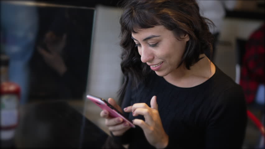 Happy Brazilian girl looking at smartphone device screen smiling