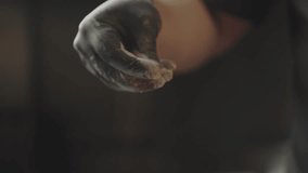 Close-up slow motion video of chef's hand peppering meat. A chef prepares and marinates raw meat in the kitchen.