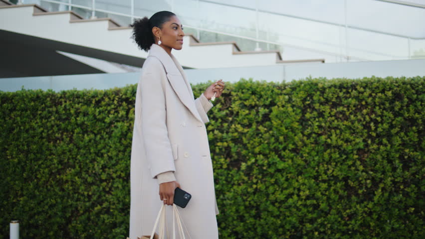Elegant woman walking street with shopping bags. Smiling black hair girl commute home holding keys. Joyful african american businesswoman enjoy evening go residential area. Wealthy lifestyle concept Royalty-Free Stock Footage #1101016167